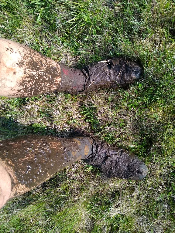 Nogi w kolarskich butach ubłocone aż po kolana.