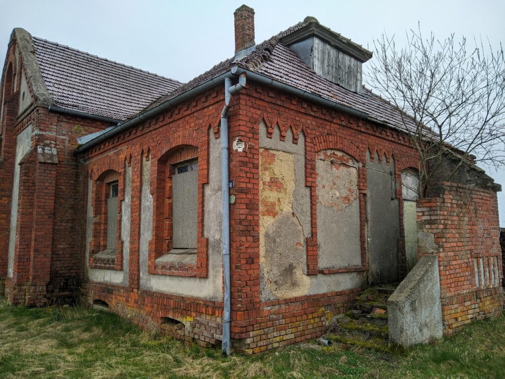 Obracamy się jeszcze bardziej w prawo, tym razem widoczna boczna ścian z wejściem do pastorówki. Ze schodów wyrasta spore drzewko.