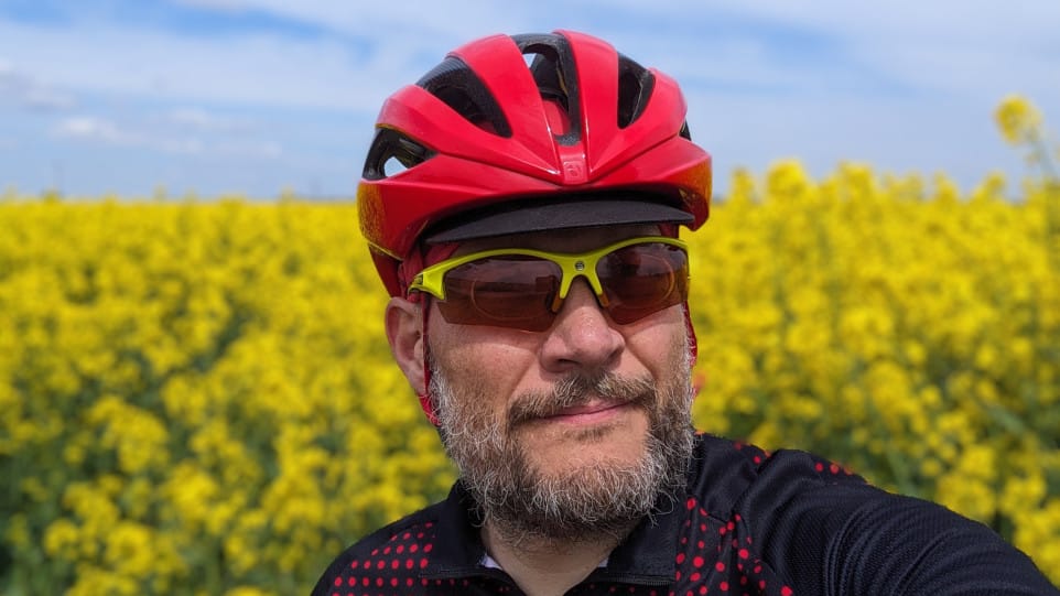 Moje selfie w czerwonym rowerowym kasku i okularach przeciwsłonecznych z żółtymi oprawkami na tle kwitnącego rzepaku.