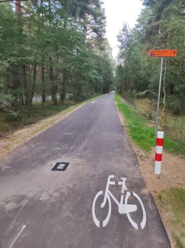Nowiutka asfaltowa droga dla rowerów prowadząca przez las. Na drogowskazie odległości do Świerczyny (10 km) i Wałcza (36 km).