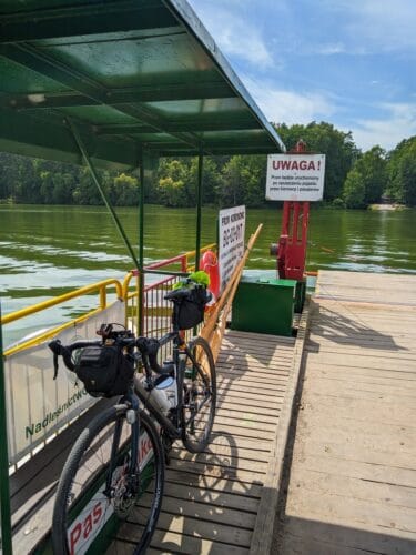 Rower oparty o barierkę na promie płynącym przez zalew.