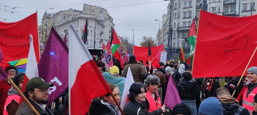 Widok na demonstrujących ludzi z flagami Polski, Palestyny, partii Razem i Akcji Socjalistycznej.