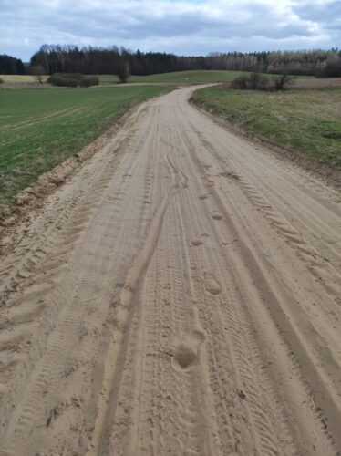 Pochmurny dzień. Bardzo piaszczysta droga przez zieleniące się pola. W piasku widać skręcające to w jedną, to w drugą ślady kół roweru, a od pewnego miejsca też i moich stóp, bo musiałem rower podprowadzić pod górkę.