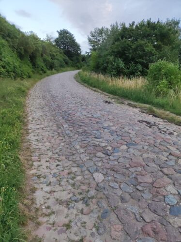 Skręcająca w prawo droga brukowana pod górę.