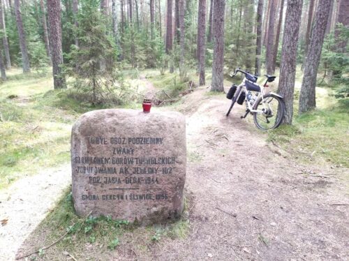 

Głaz z napisem "Tu był obóz podziemny zwany garnizonem Borów Tucholskich zgrupowania AK Jrdliny-102 por. Jasia-Dęba - 1944”. W tle stoi mój rower, oparty o drzewo.